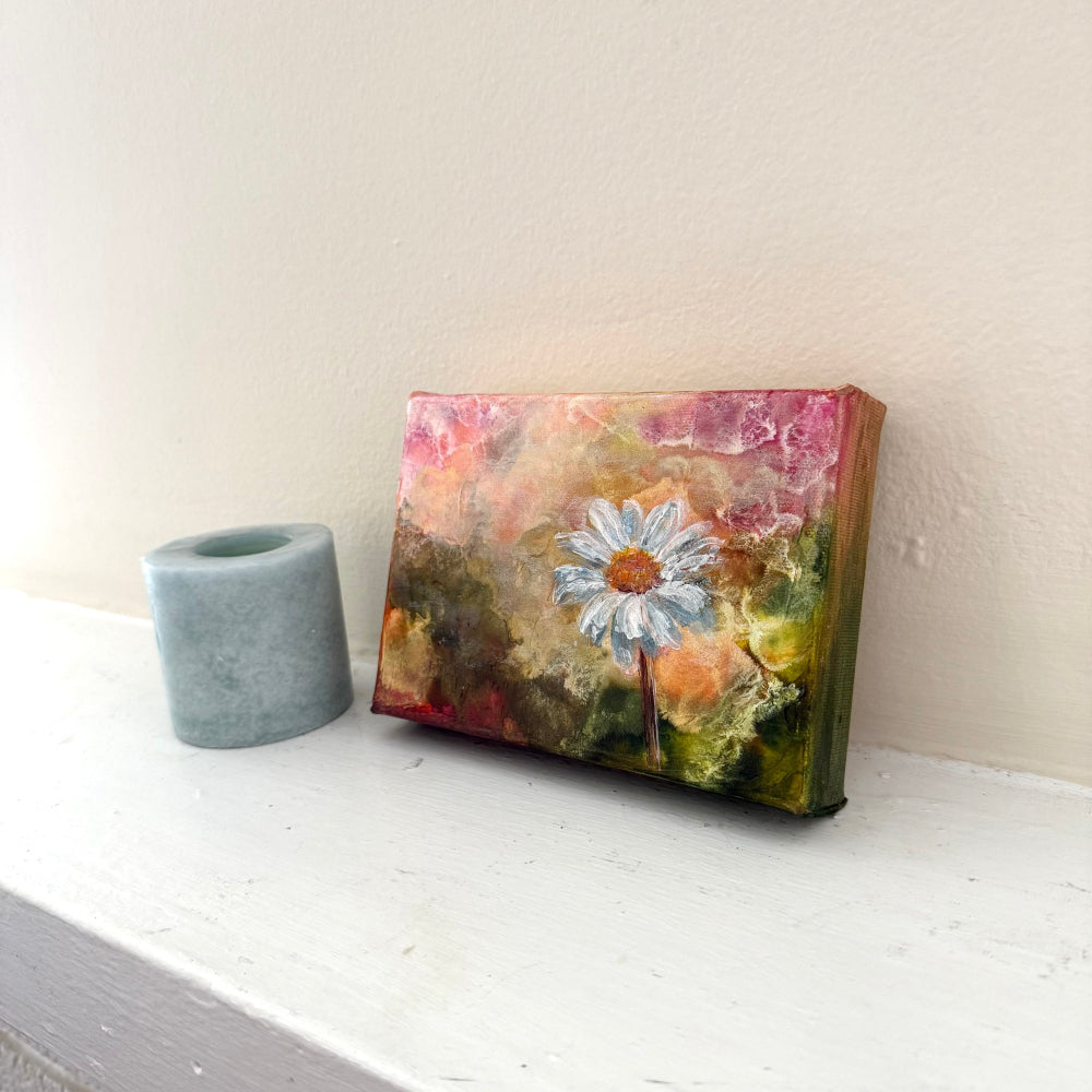 Small floral painting on a white surface with a neutral background side angle shot