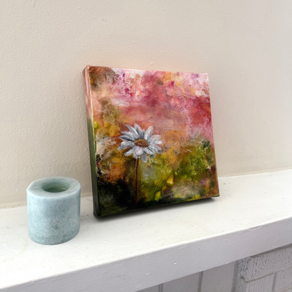 Abstract painting of a flower on a white surface with a light gray candle side angle