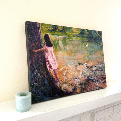 Angled view of a textured acrylic palette knife painting showing canvas depth next to candle, featuring a girl in a pink dress watching birds by the water.