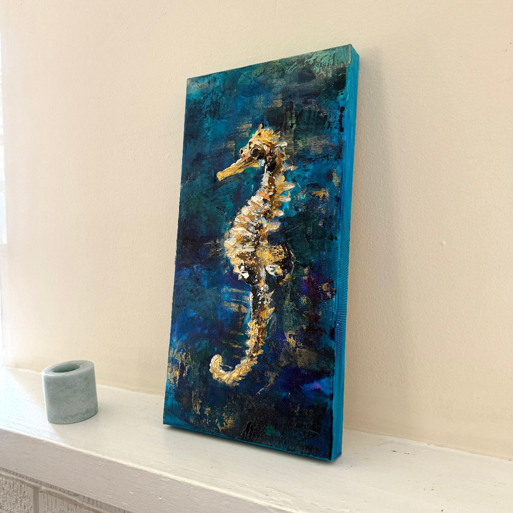 Canvas painting of a seahorse on a blue and green background, displayed on a white surface.