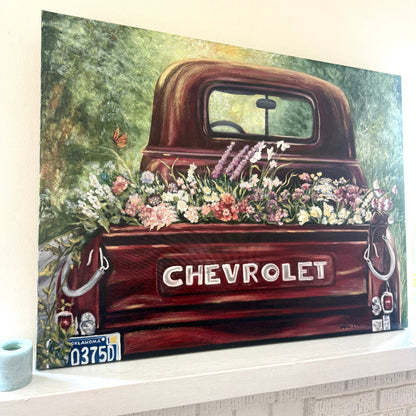 Oil Painting Old Vintage Red Chevrolet truck with a variety of flowers in the bed on a decorative mantle piece next to a candle, lots of Reds, pinks, greens.