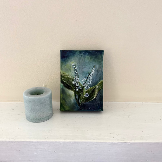 Lily of the Valley flower floral acrylic palette knife painting by Allison Victoria deep greens and blues cool colors on gallery wrapped canvas styled delicately next to a blue candle on a neutral mantle home decor