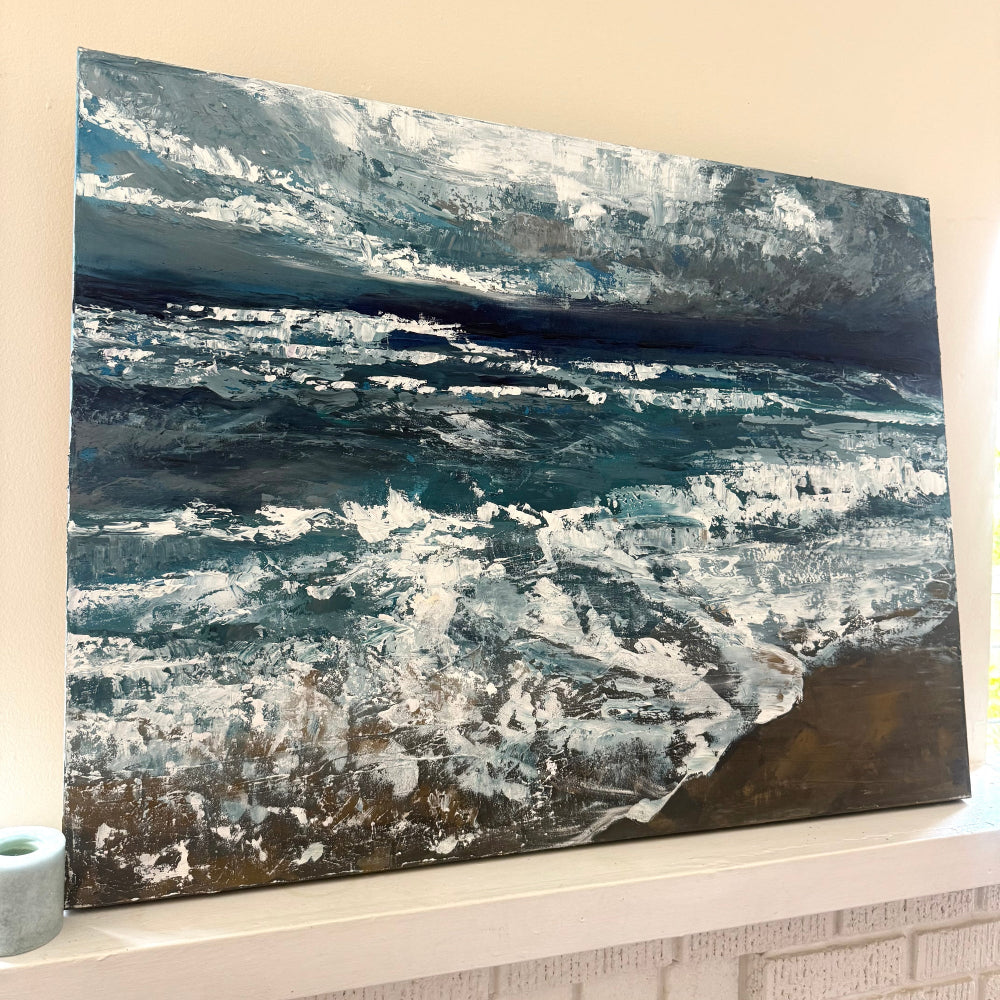Abstract ocean art piece with blue and white tones on a beige wall and mantle side angle