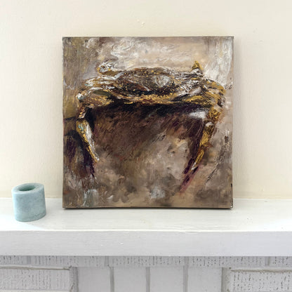 Abstract coastal crab acrylic palette knife painting with gold and brown tones on a white shelf against a light wall.