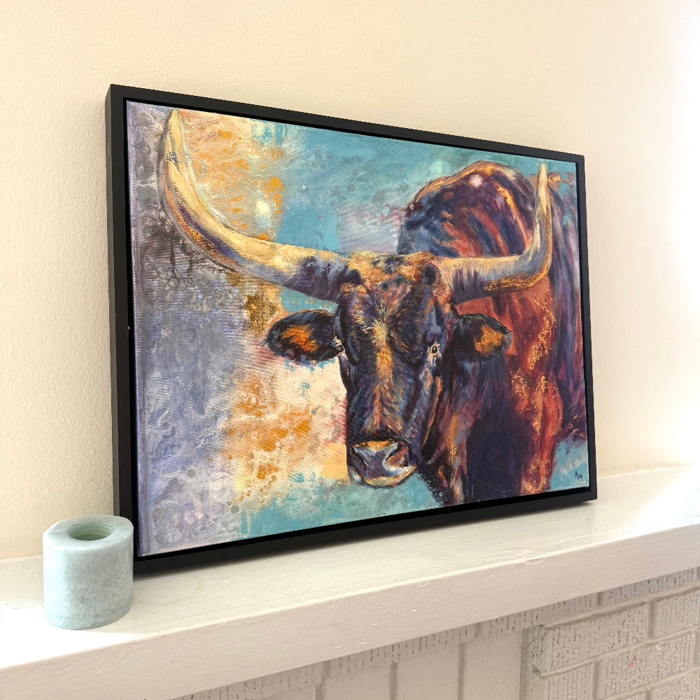 Framed vibrant bold painting of a Wichita Longhorn on a neutral mantle next to candle