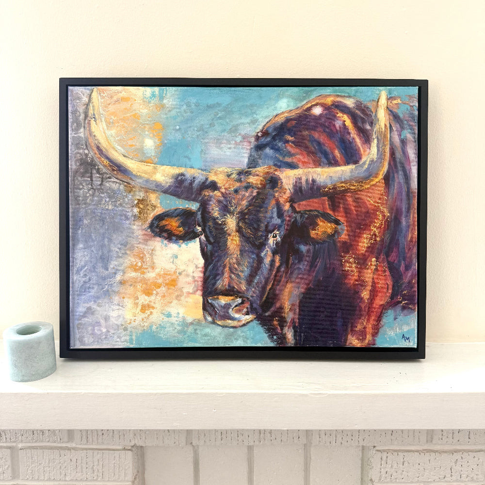 Framed vibrant bold painting of a Wichita Longhorn on a neutral mantle next to candle