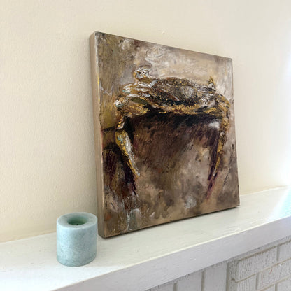 Abstract coastal crab acrylic palette knife painting with gold and brown tones on a white shelf against a light wall.